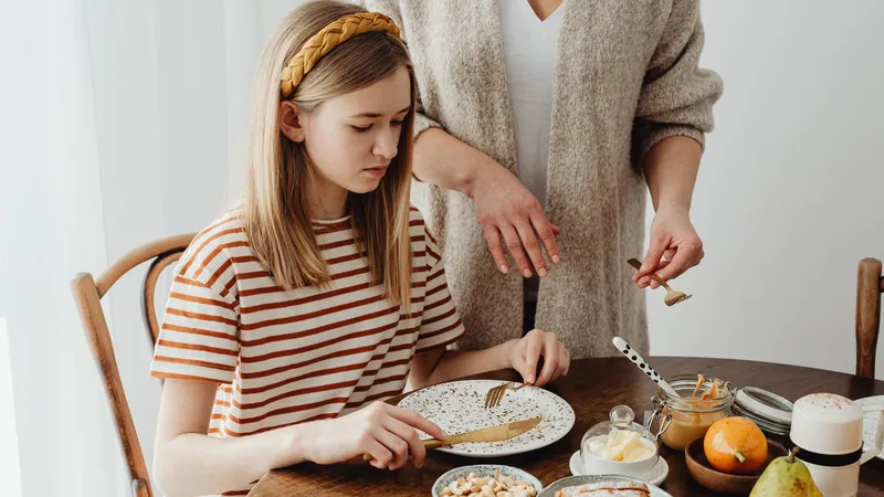 Yemek sonrası karın şişkinliği hissederken belini gevşetip karnını tutan bir kadın