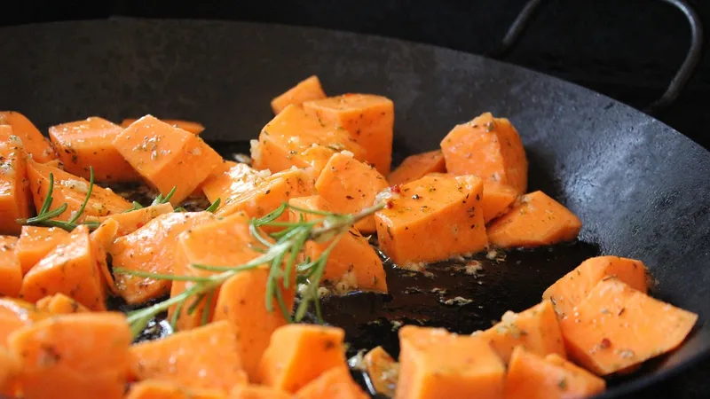 Paleo diyeti için balık, tatlı patates ve sebzelerle ev mutfağında öğün hazırlayan bir kişi