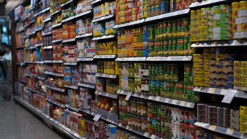 Ultra işlenmiş gıda seçimini anlamak için markette iki farklı ürünün etiketini karşılaştıran kadın