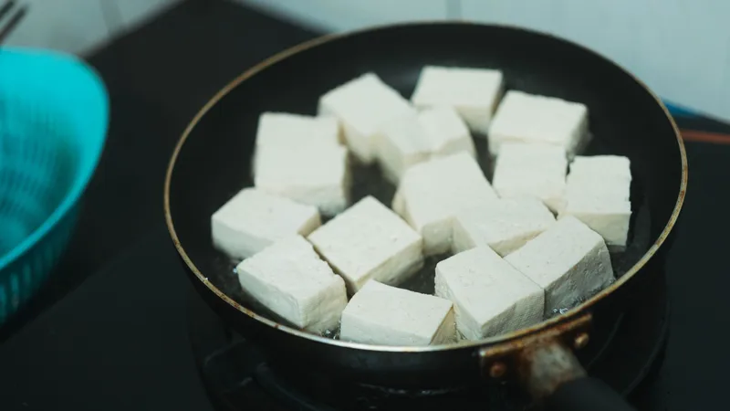 Vegan sporcu beslenmesi için mutfakta tofu, tahıl ve sebzelerle toparlanma öğünü hazırlayan sporcu